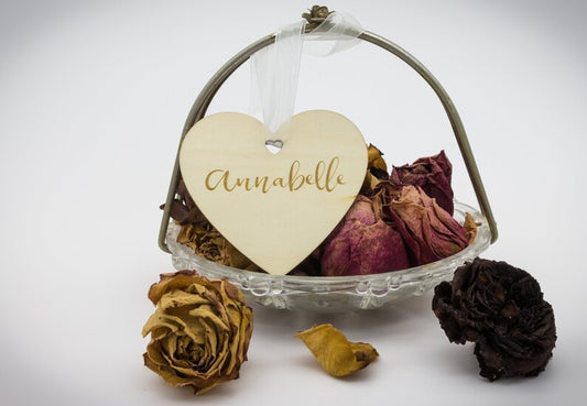 Engraved wooden heart tag on flowers.